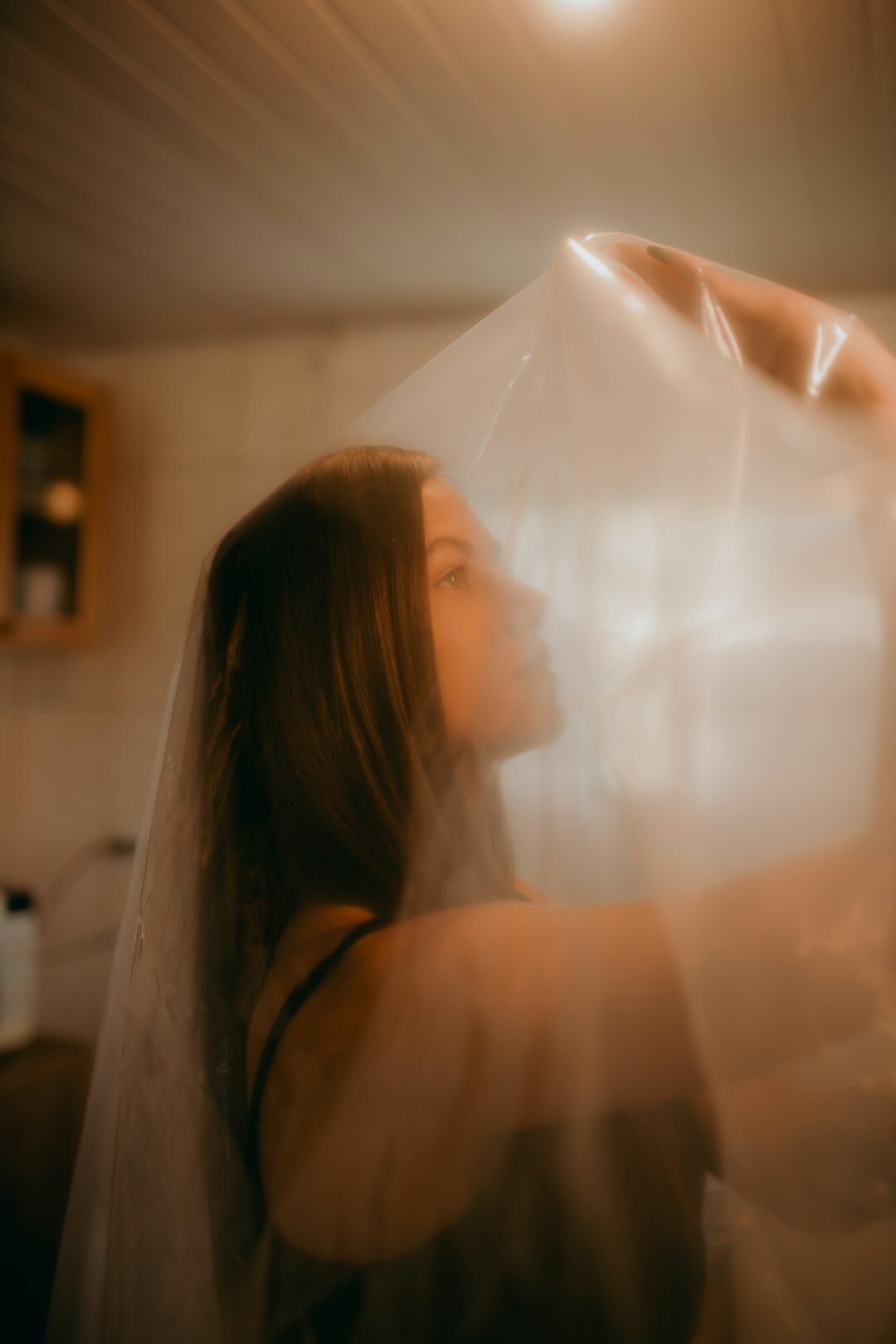 Bride adjusting veil in soft window light before ceremony