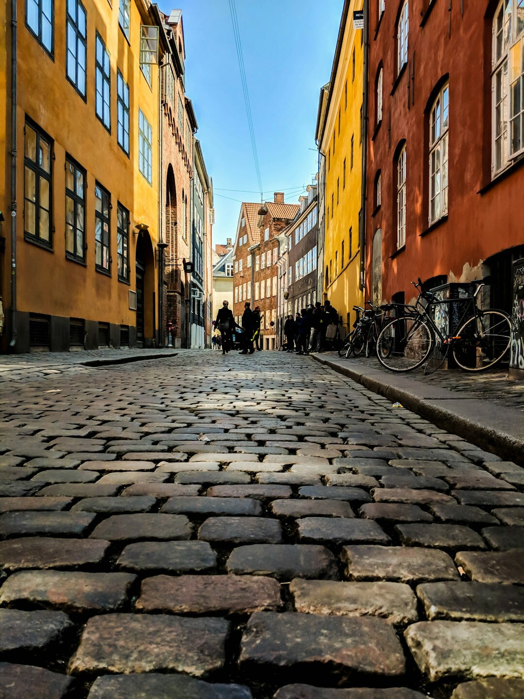 Pedestrians crossing a cobbled street in central Copenhagen