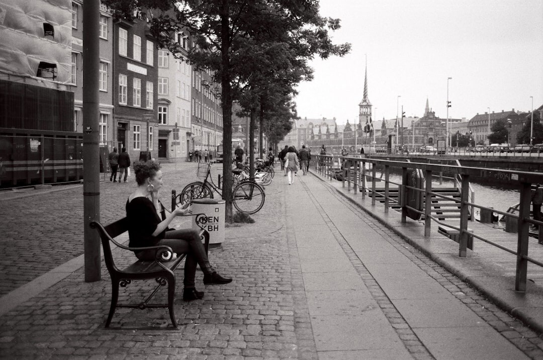 Elderly Danish man reading a newspaper on a city bench