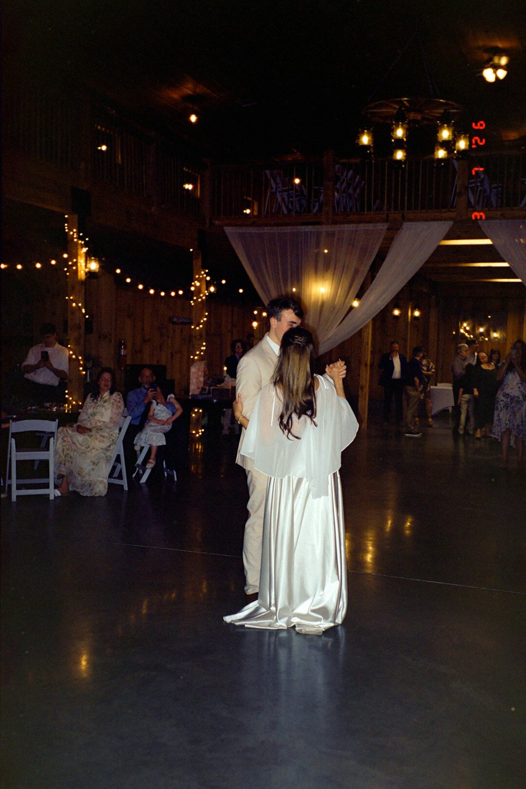 Wedding guests dancing at an evening reception in a barn
