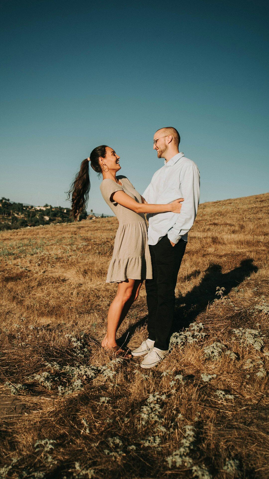 Couple laughing together in a sunlit meadow