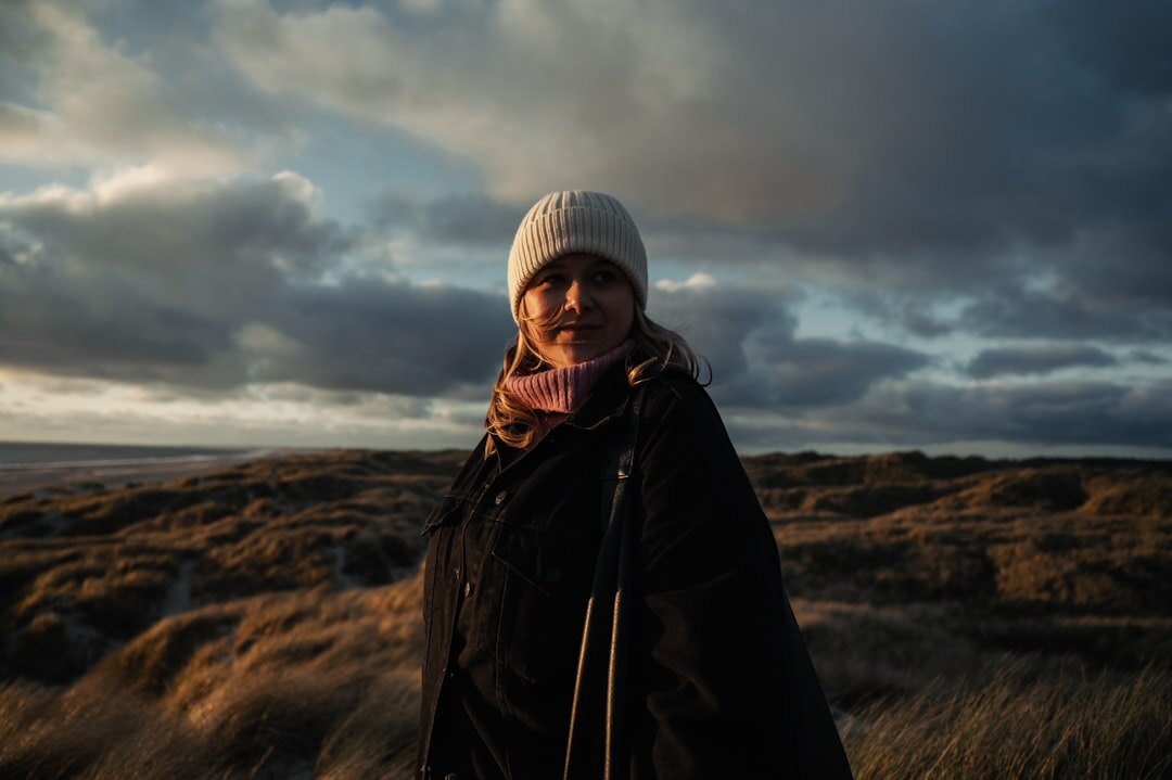 Portrait of a 35 year old Danish female photographer holding a camera and smiling softly